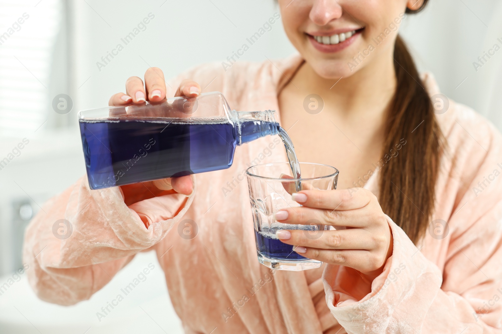 Photo of Young woman using mouthwash indoors, closeup view