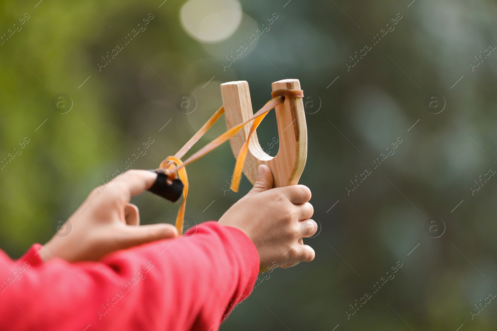 Photo of Little boy playing with slingshot outdoors, closeup