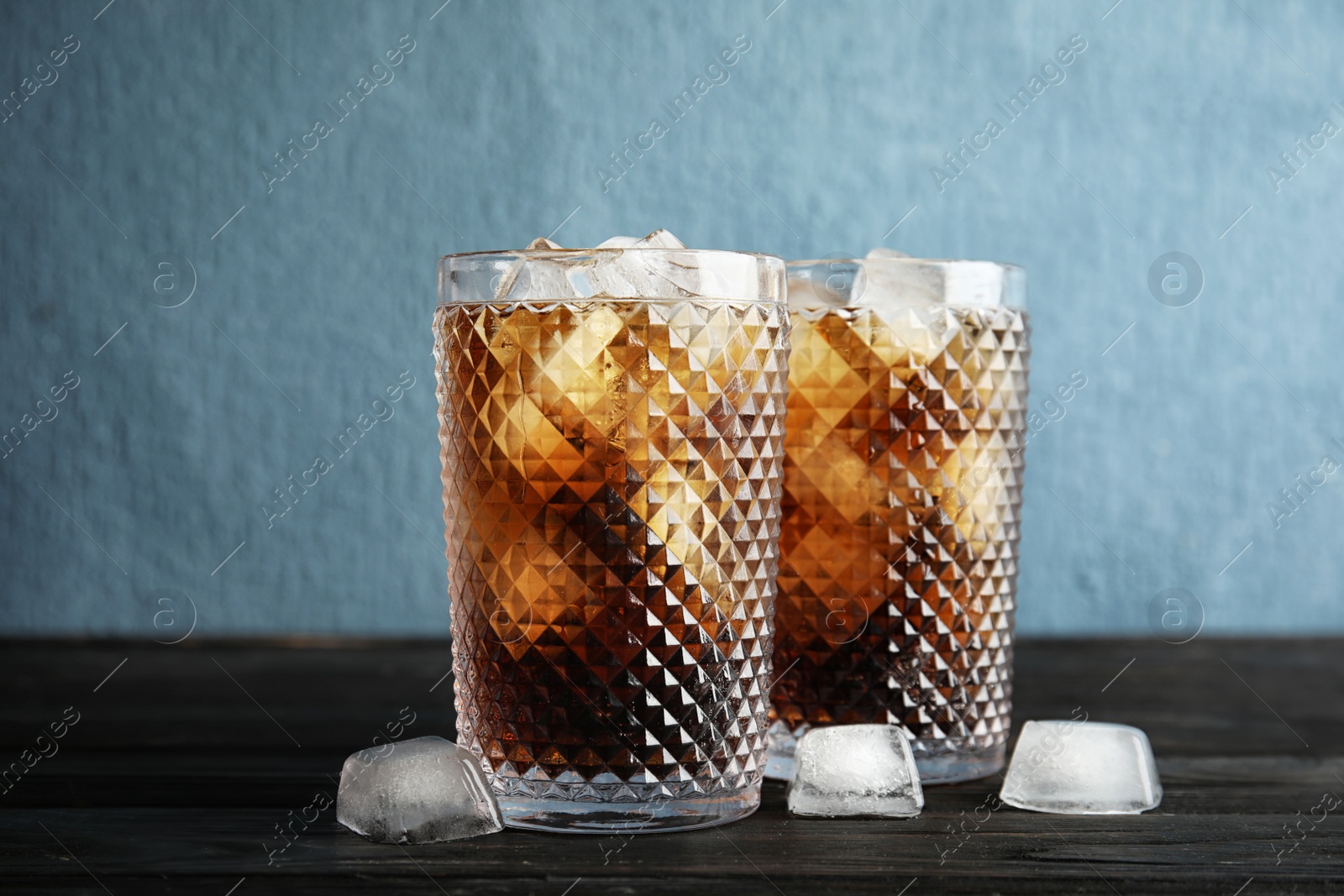 Photo of Glasses of refreshing cola with ice cubes on table