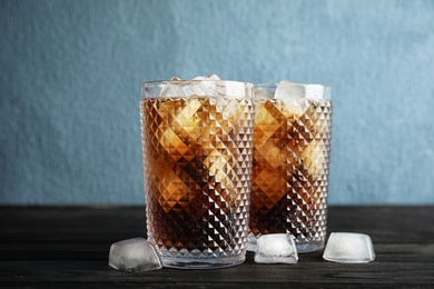 Glasses of refreshing cola with ice cubes on table