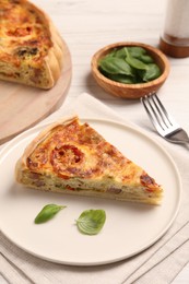 Photo of Delicious homemade vegetable quiche and basil leaves on plate