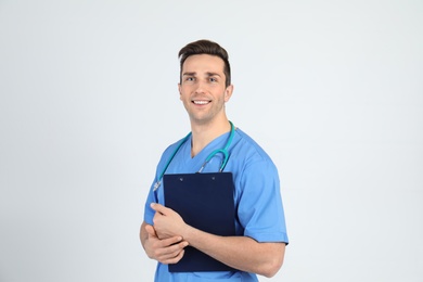 Portrait of medical assistant with stethoscope and clipboard on light background