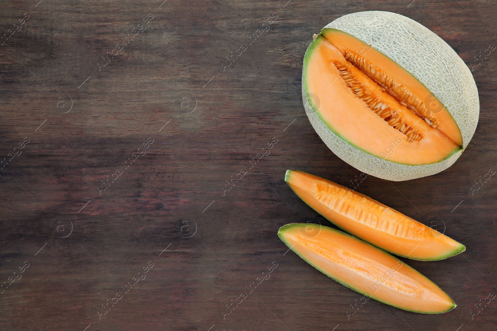 Photo of Cut delicious ripe melon on wooden table, flat lay. Space for text