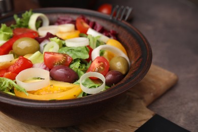 Photo of Bowl of tasty salad with leek and olives on brown table, closeup