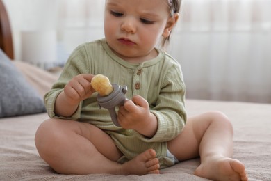 Cute baby girl with nibbler on bed at home