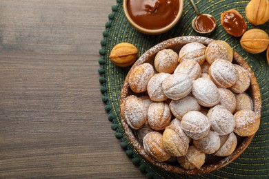Photo of Bowl of delicious nut shaped cookies with boiled condensed milk on wooden table, flat lay. Space for text