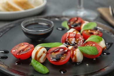 Photo of Fresh vegetable salad with mozzarella and balsamic vinegar on plate, closeup