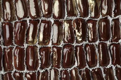 Many delicious eclairs with chocolate icing as background, top view