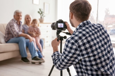 Photo of Professional photographer taking photo of family on sofa in studio