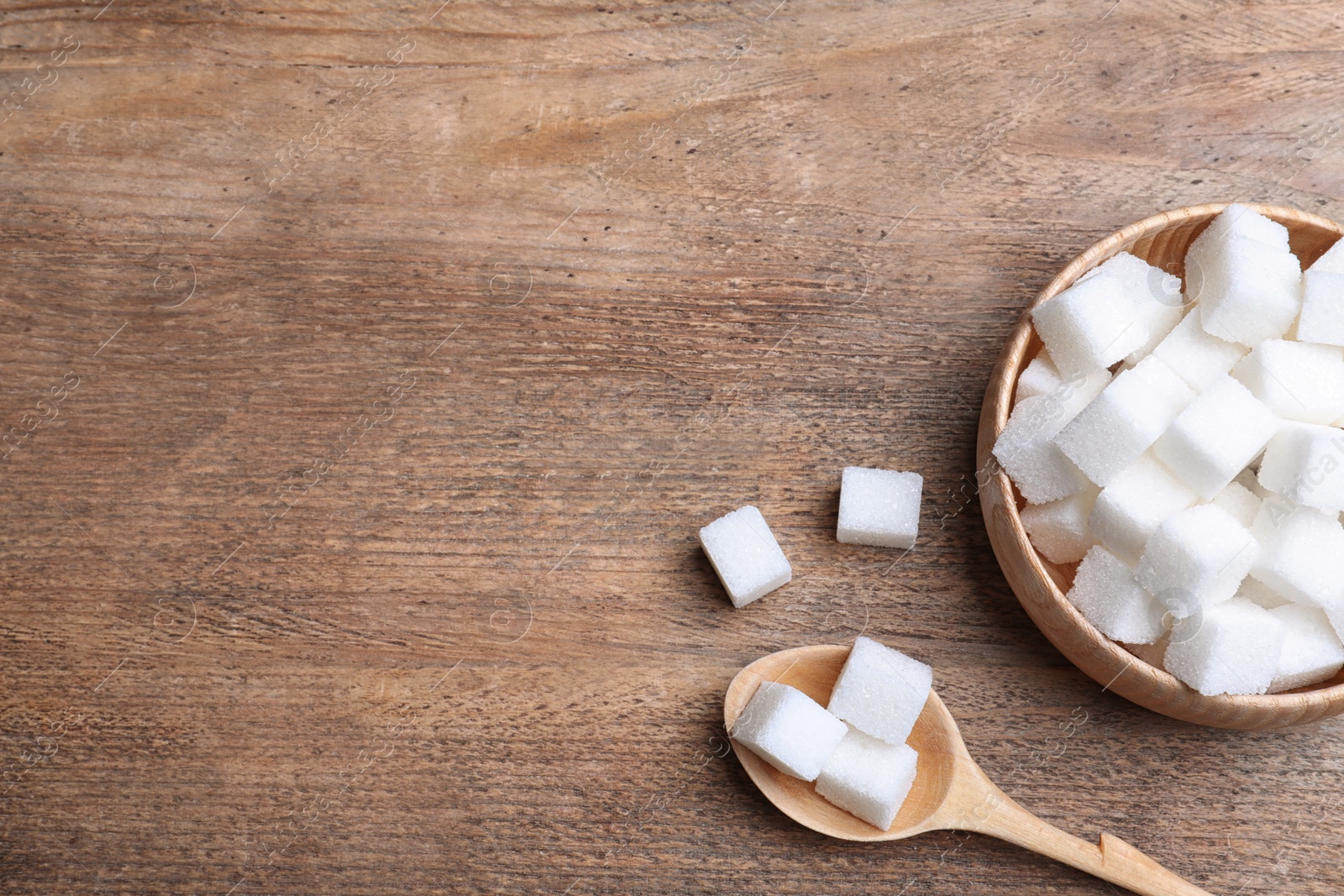 Photo of Refined sugar on wooden table, flat lay. Space for text