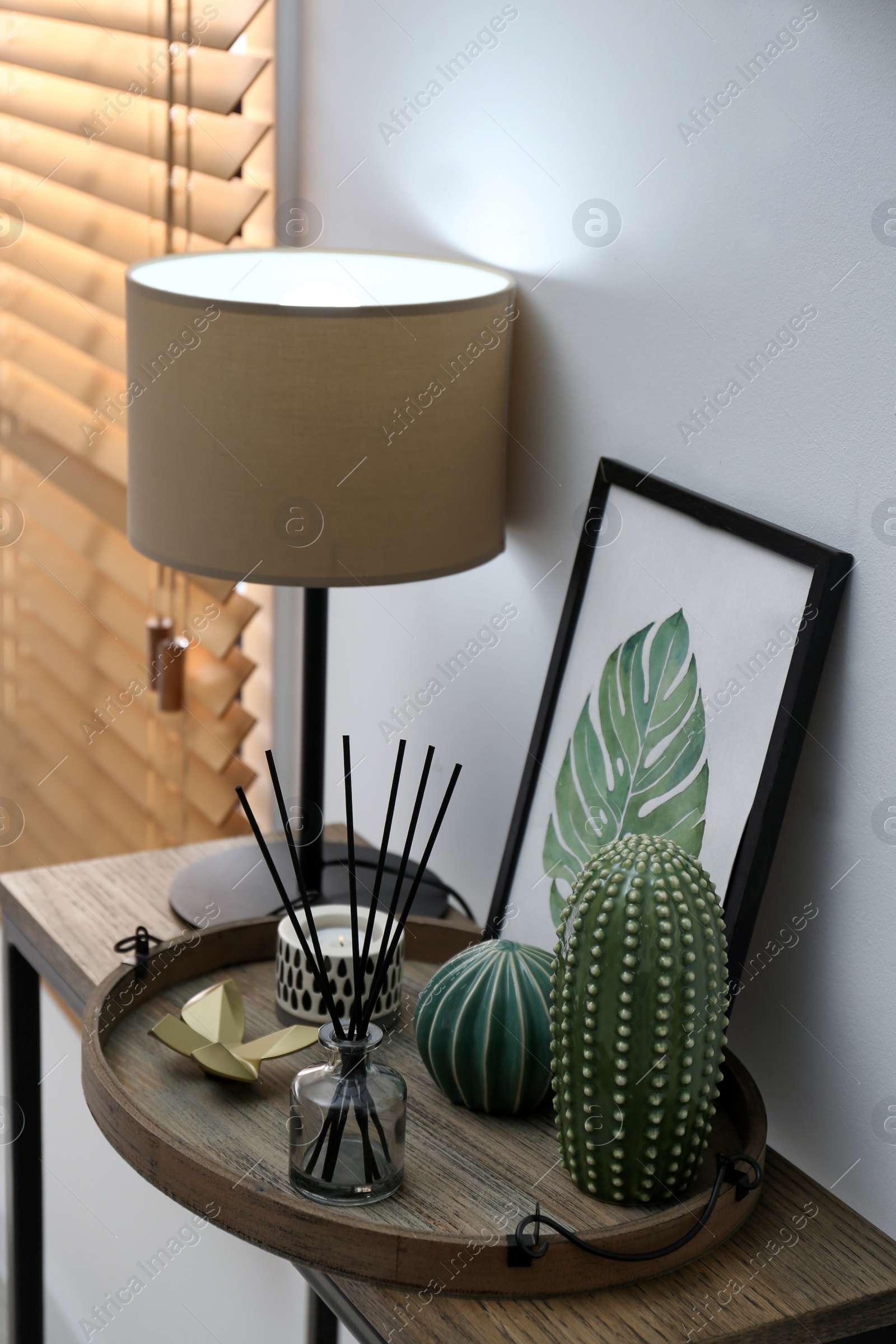 Photo of Wooden tray with decorations and lamp on table indoors