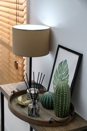 Wooden tray with decorations and lamp on table indoors