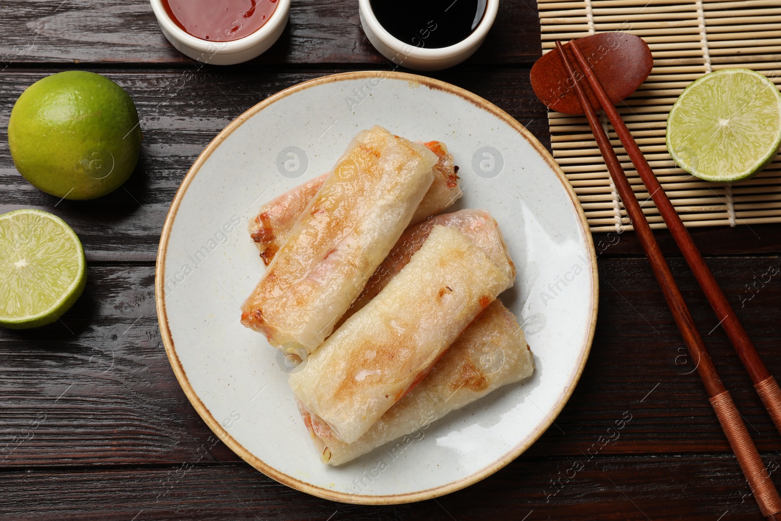 Photo of Delicious fried spring rolls served on wooden table, flat lay