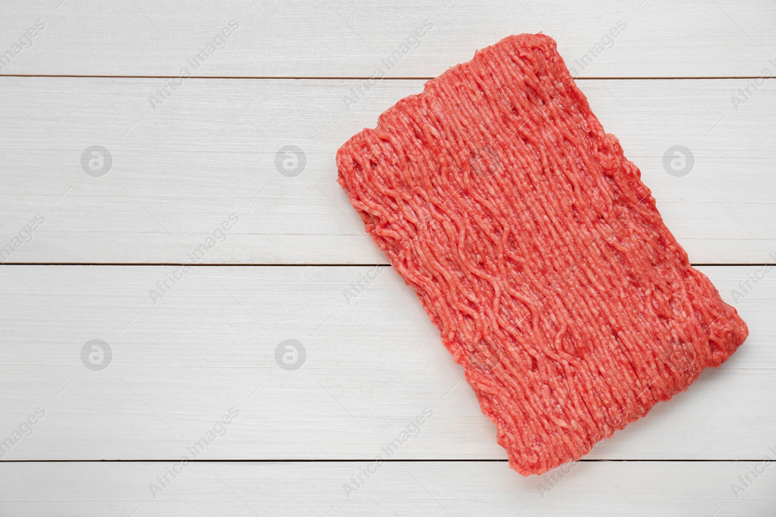 Photo of Raw fresh minced meat on white wooden table, top view. Space for text