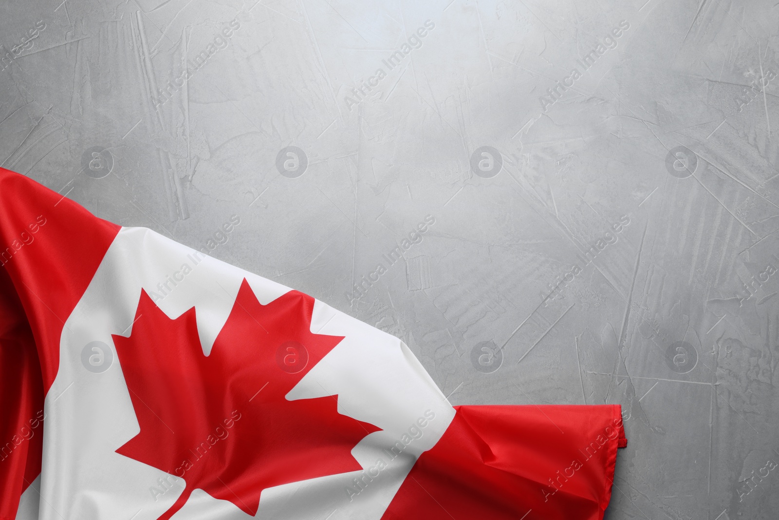 Photo of Flag of Canada on light grey stone table, top view. Space for text