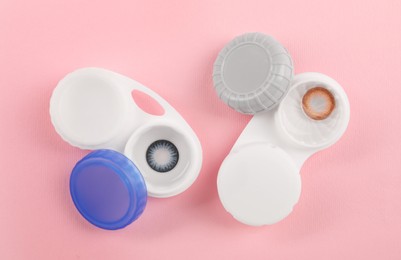 Photo of Cases with color contact lenses on pink background, flat lay