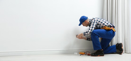 Photo of Professional electrician repairing power socket in room