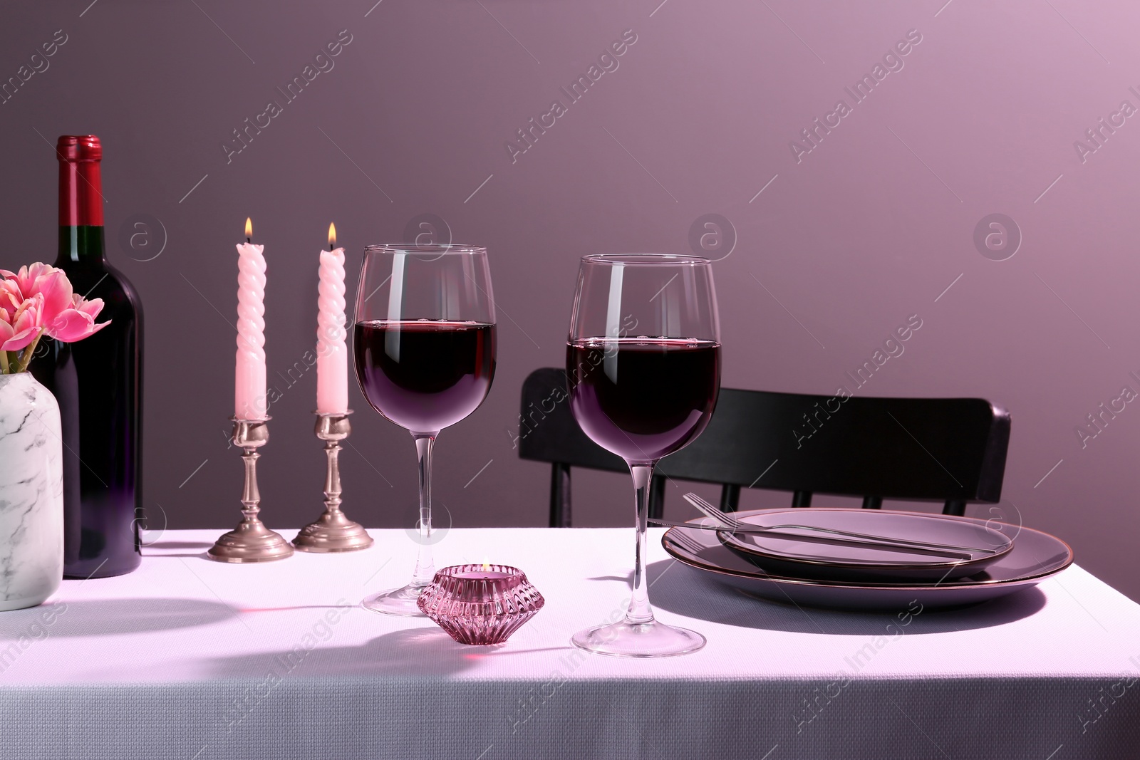 Photo of Romantic table setting with glasses of red wine and candles indoors