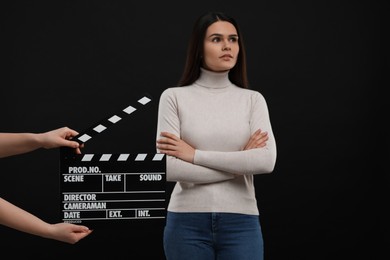 Photo of Actress performing while second assistant camera holding clapperboard on black background. Film industry