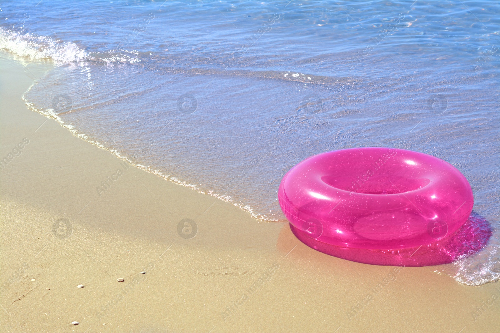 Photo of Bright inflatable ring on sandy beach near sea. Space for text