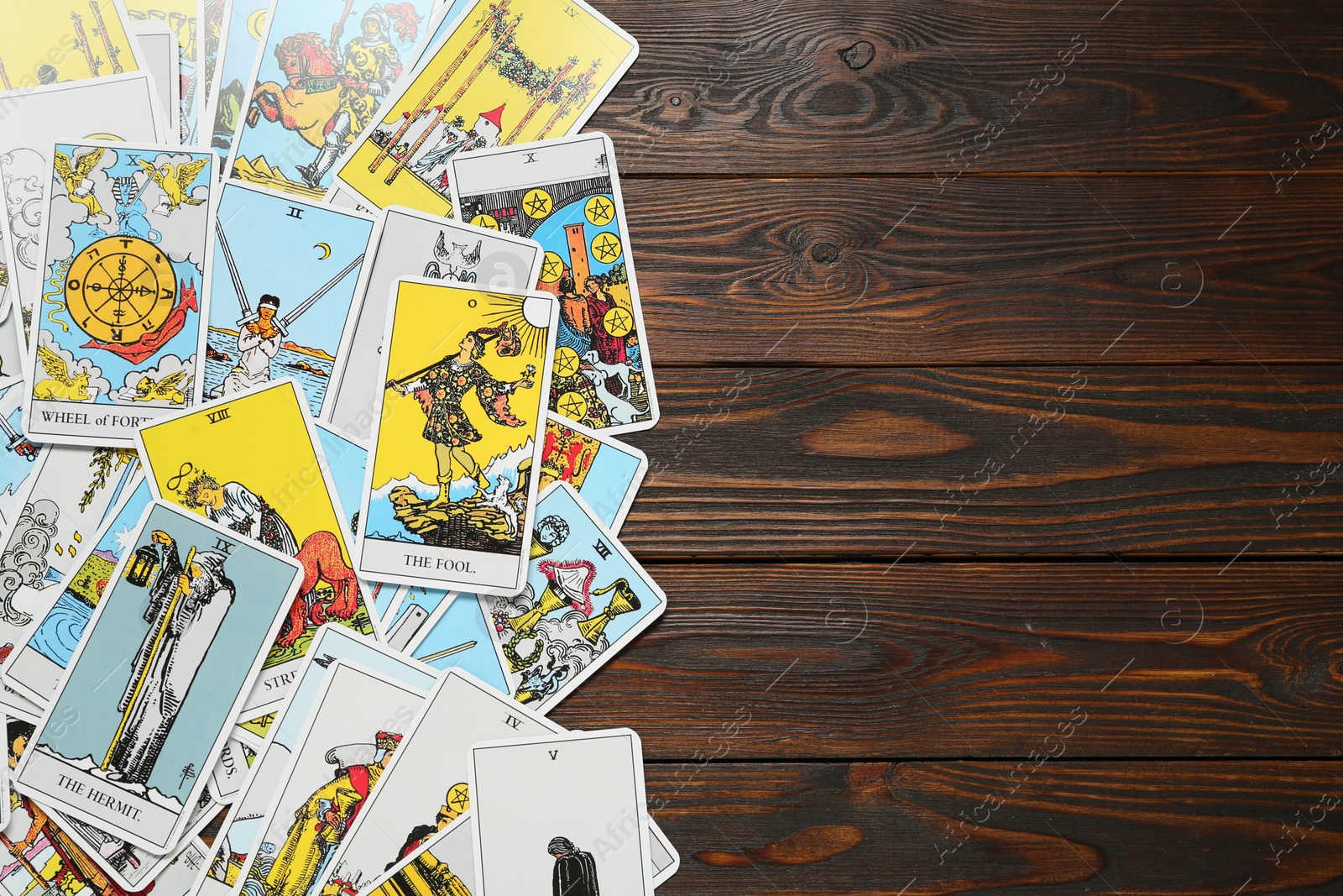 Photo of Tarot cards on wooden table, top view. Space for text