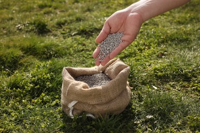 Man with fertilizer on green grass outdoors, closeup