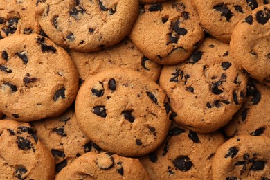 Delicious chocolate chip cookies as background, top view