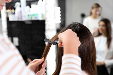 Professional hairdresser working with client in beauty salon, closeup