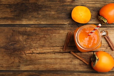 Tasty persimmon smoothie and fresh fruits on wooden table, flat lay. Space for text