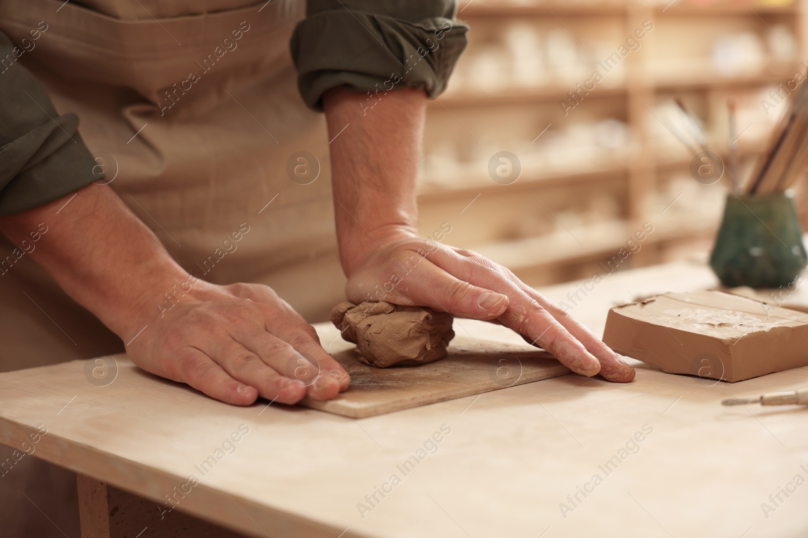 Photo of Man crafting with clay at table indoors, closeup
