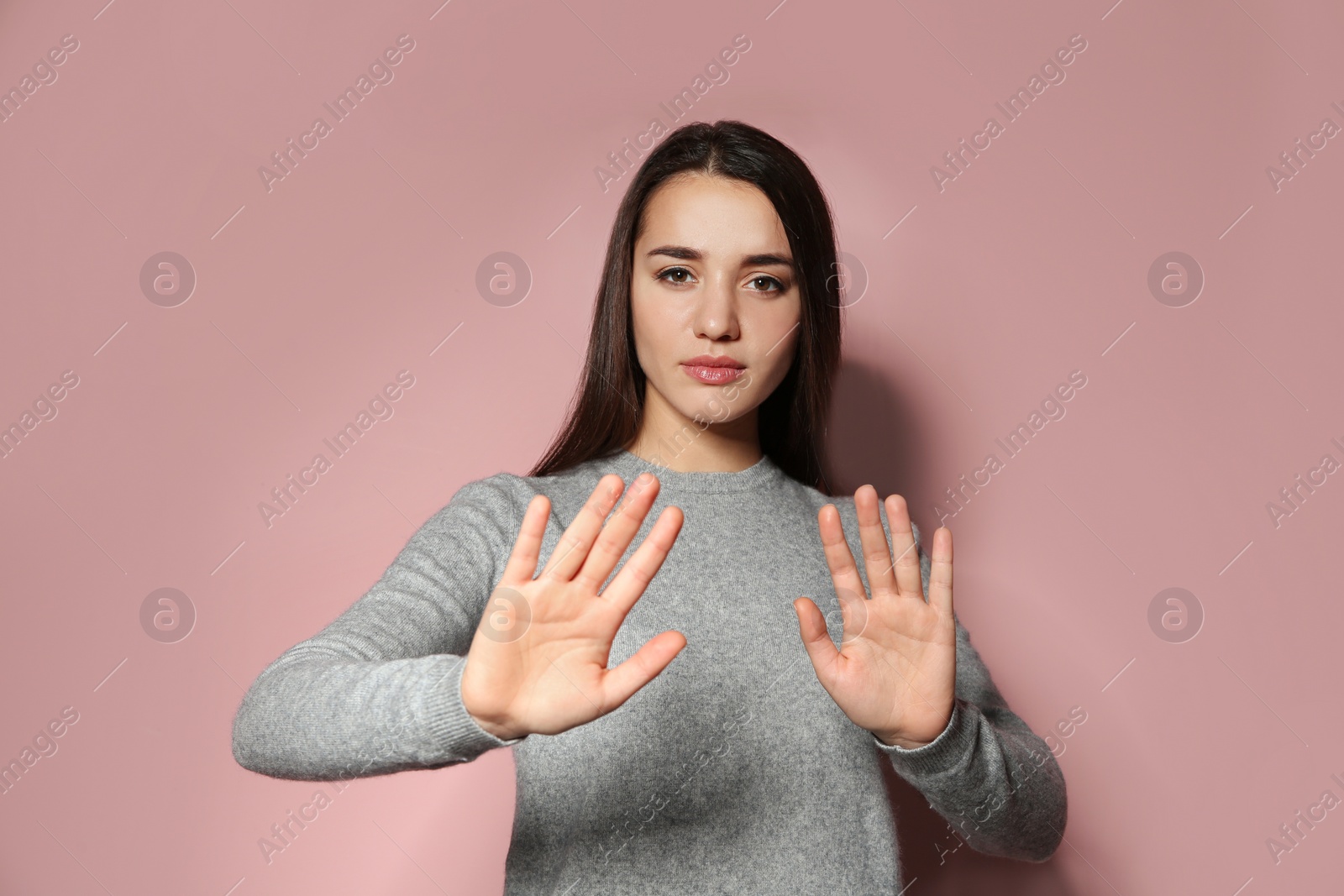 Photo of Woman showing STOP gesture in sign language on color background