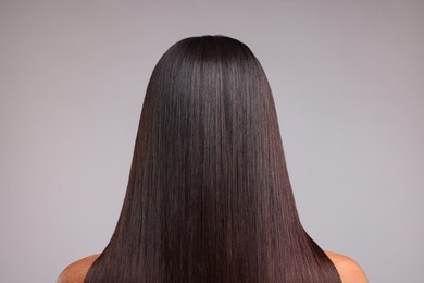 Photo of Woman with healthy hair after treatment on light gray background, back view