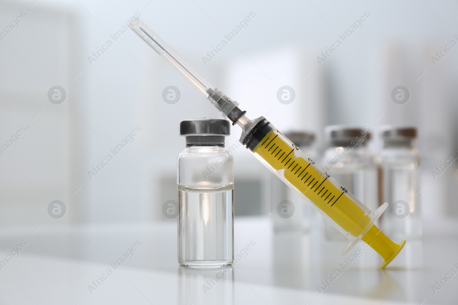 Photo of Syringe and vial of medicine on white table, closeup