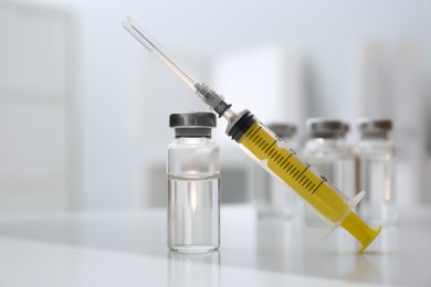 Syringe and vial of medicine on white table, closeup