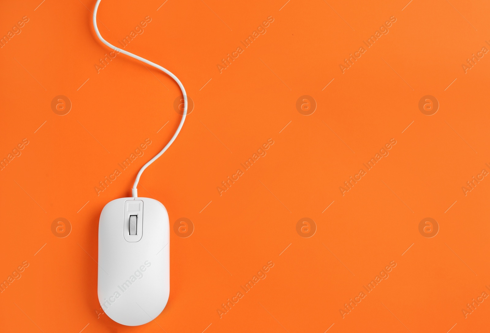 Photo of Modern wired optical mouse on orange background, top view. Space for text