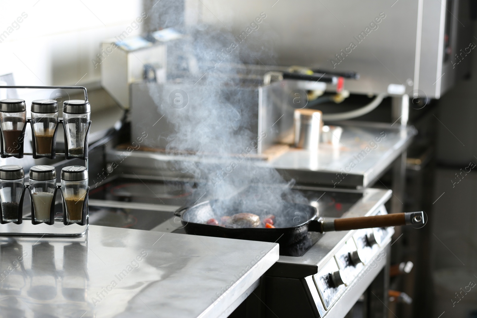 Photo of Cooking meat on frying pan in restaurant kitchen