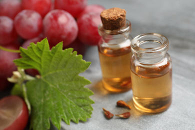 Photo of Bottles of natural grape seed oil on grey table. Organic cosmetic