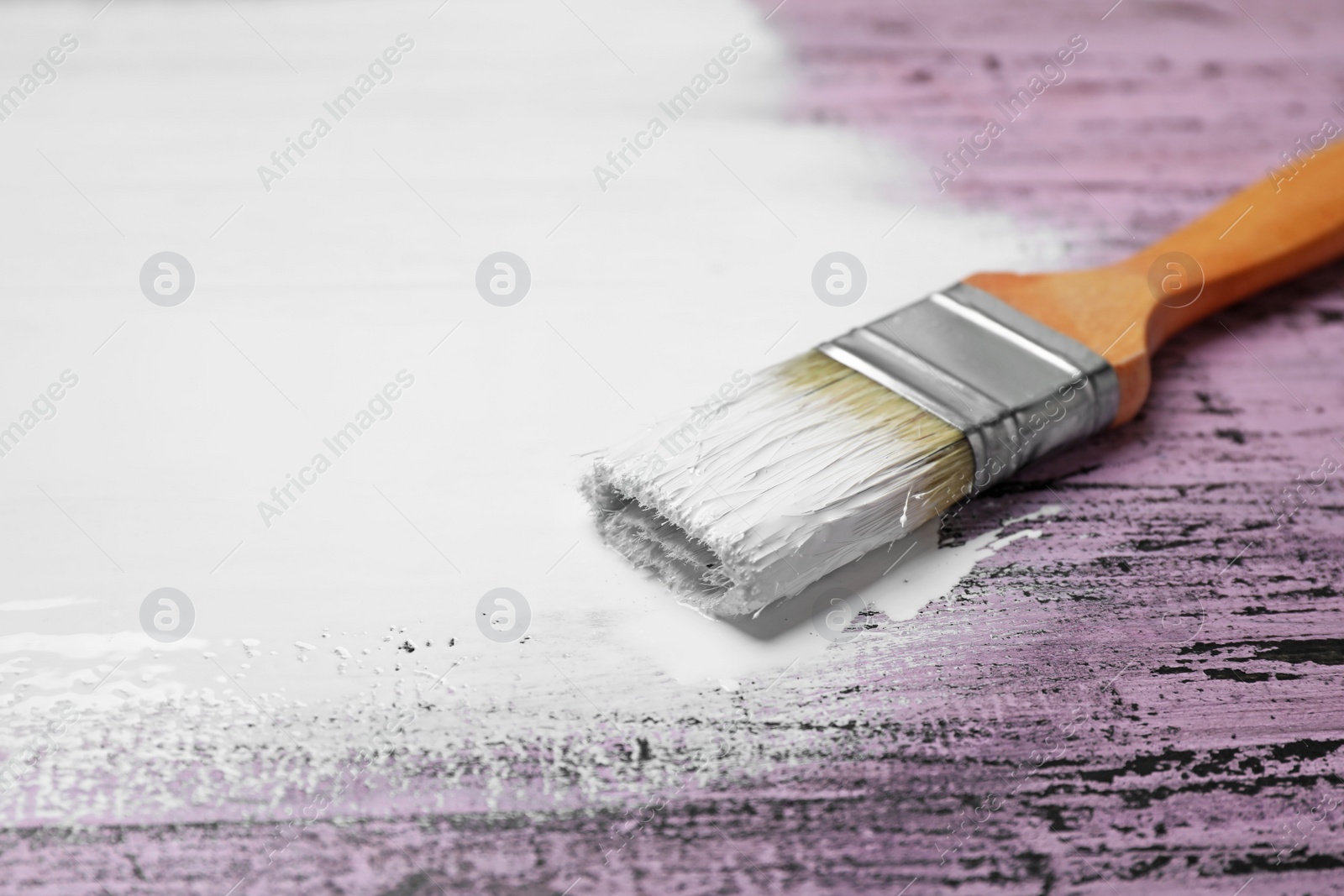 Photo of Brush with white paint on pink wooden background, space for text