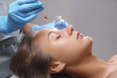 Photo of Cosmetologist applying serum on client's face in salon