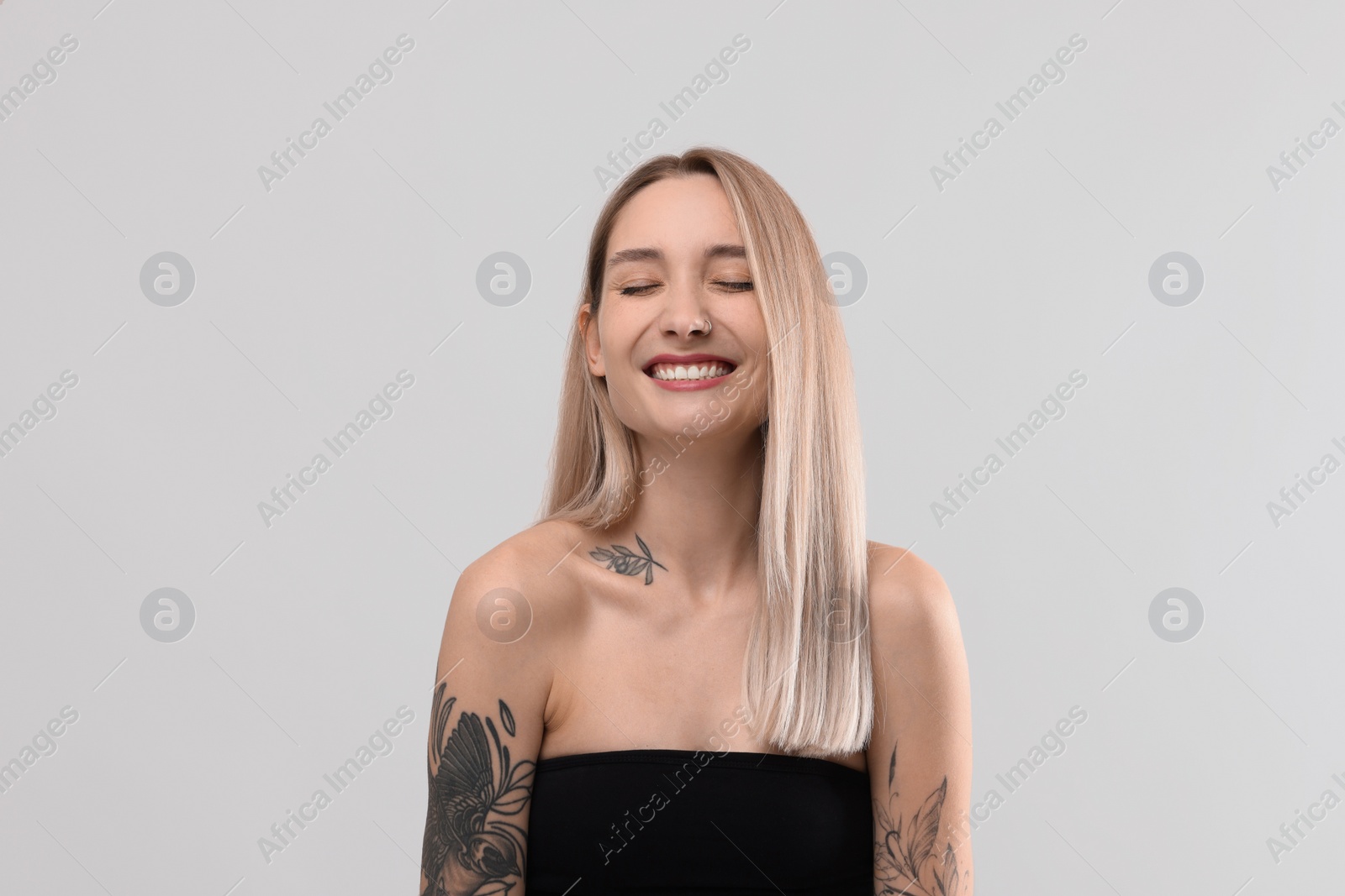 Photo of Portrait of beautiful tattooed woman on light background