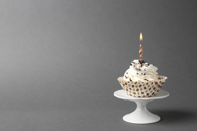 Photo of Delicious birthday cupcake with candle on grey background. Space for text
