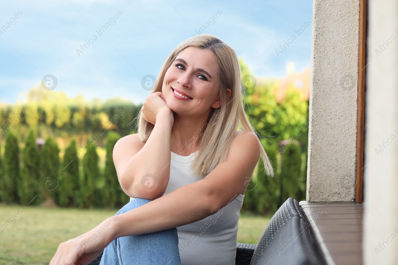 Photo of Portrait of beautiful woman sitting near house in yard, space for text