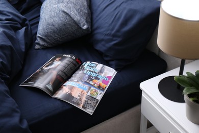 Photo of Open magazine on bed with stylish silky linens