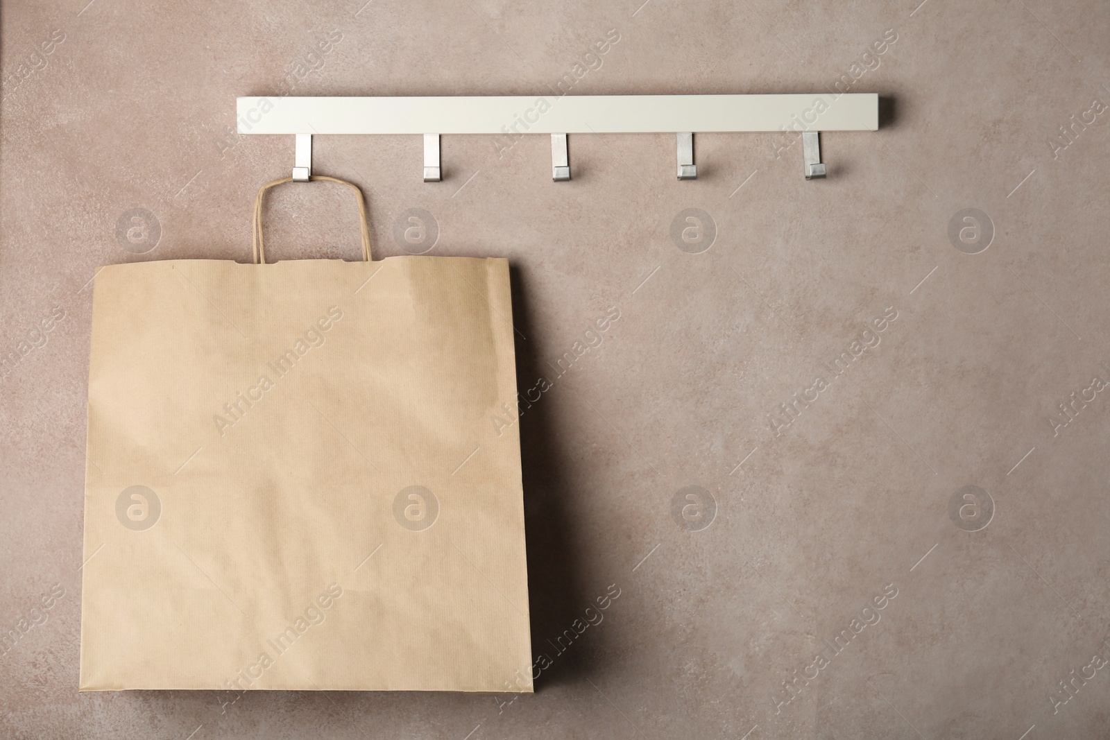 Photo of Rack with paper shopping bag on color wall