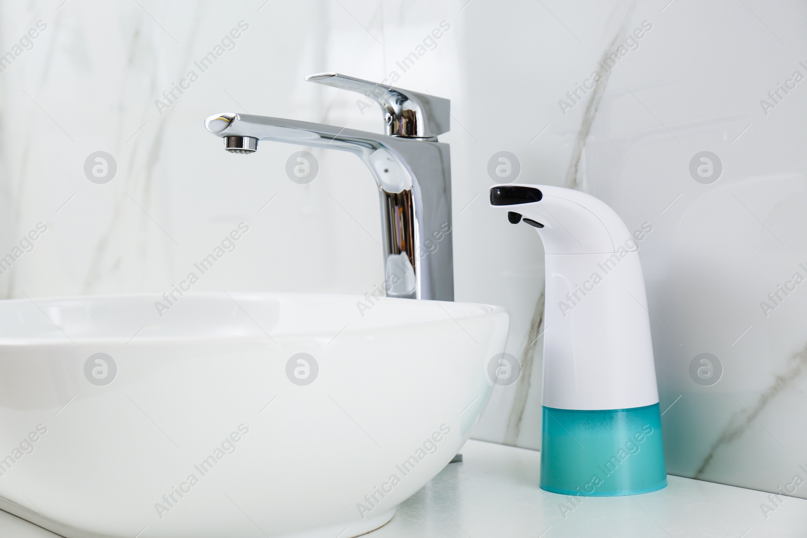 Photo of Modern automatic soap dispenser near sink in bathroom, closeup