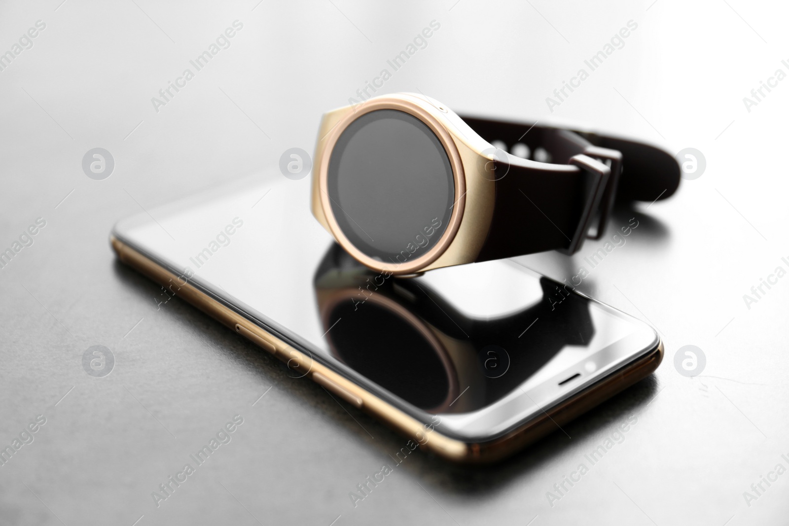 Stylish smart watch and phone on grey table, closeup Photo of Stylish smart watch and phone on grey table, closeup