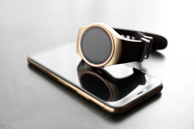 Photo of Stylish smart watch and phone on grey table, closeup