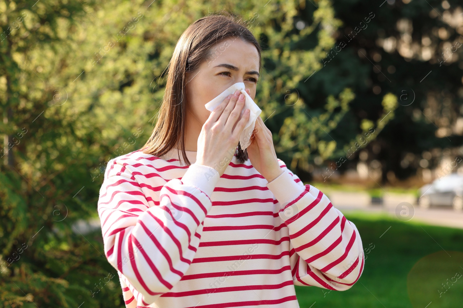 Photo of Woman with napkin suffering from seasonal allergy outdoors