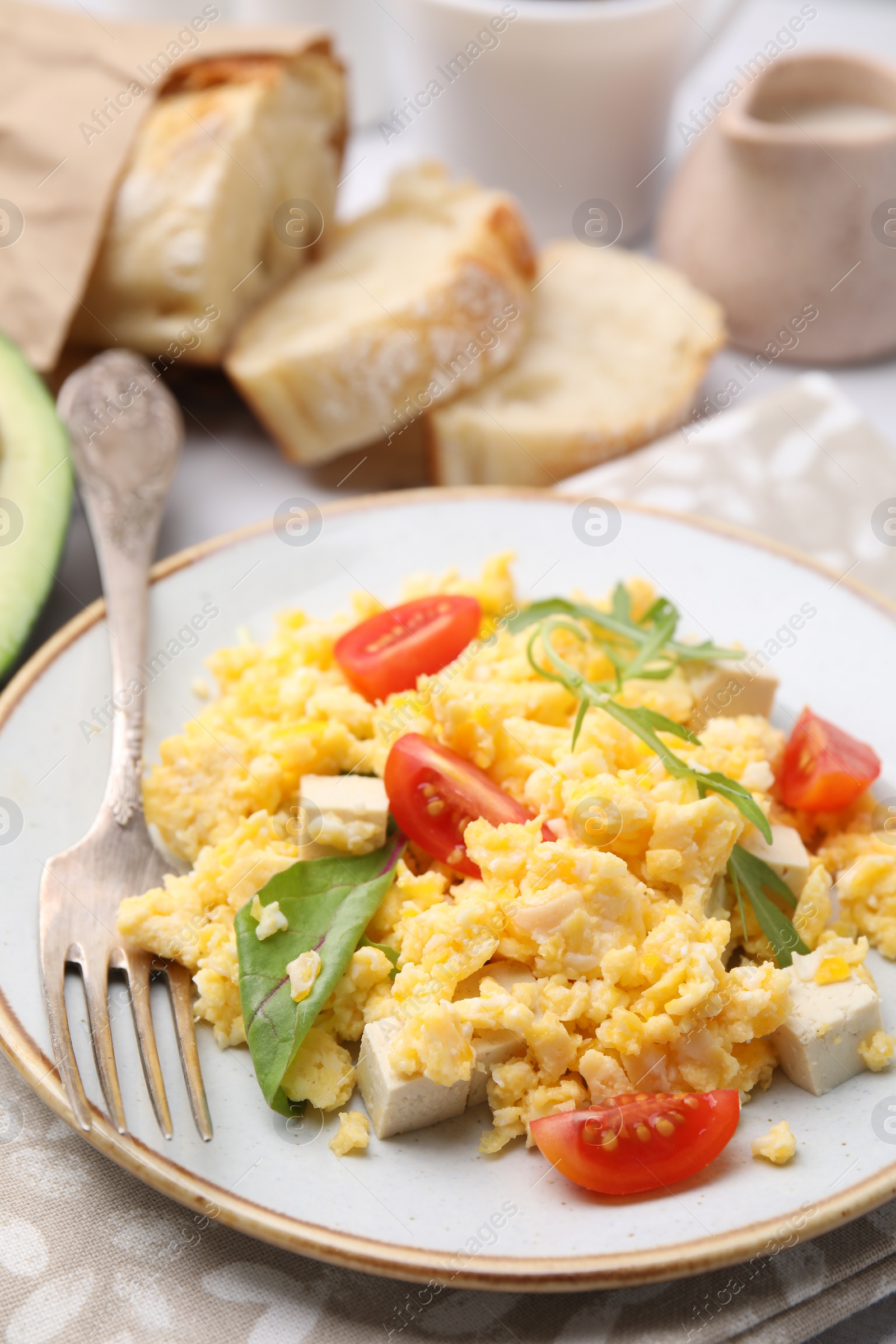 Photo of Plate with delicious scrambled eggs, tofu and tomatoes on table, closeup