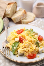 Plate with delicious scrambled eggs, tofu and tomatoes on table, closeup